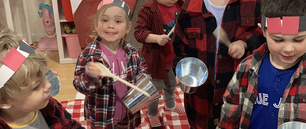 Enfants jouant de la musique avec des cuillère de bois et une chaudière dans un décor de cabane à sucre